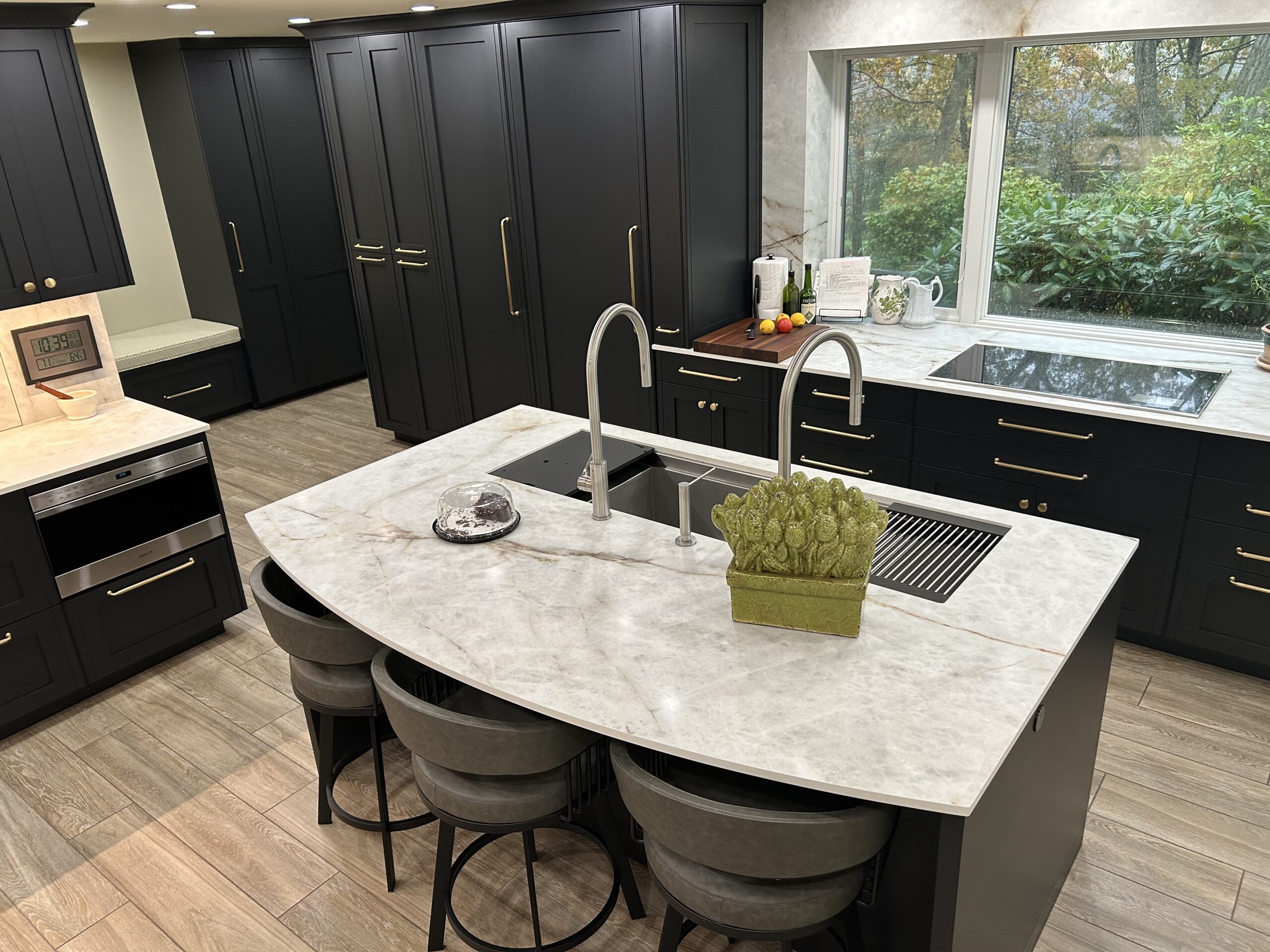 Black kitchen with white counters , large window and island sink